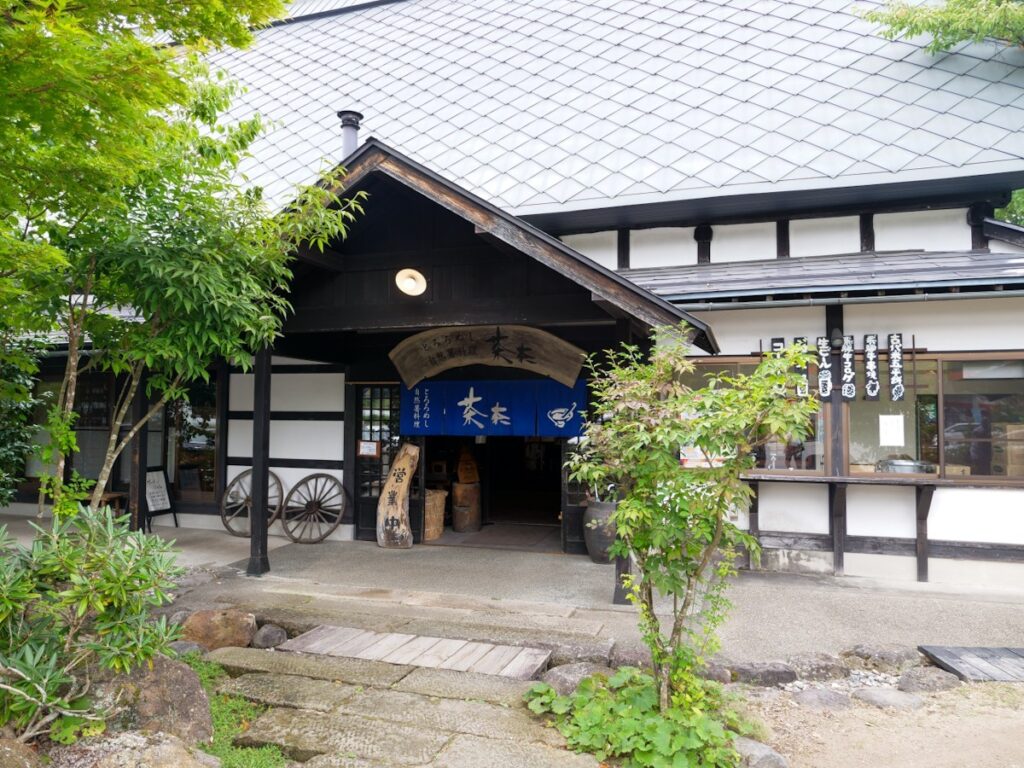 自然薯 茶茶 じねんのむら 飛騨高山店の入口と青いのれん・荷車の車輪